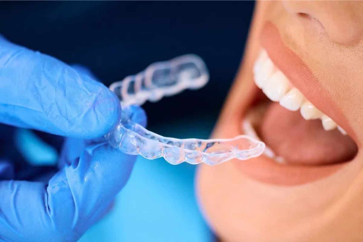 Patient holding clear Invisalign aligner tray next to smile in Lenexa, Kansas dental office.